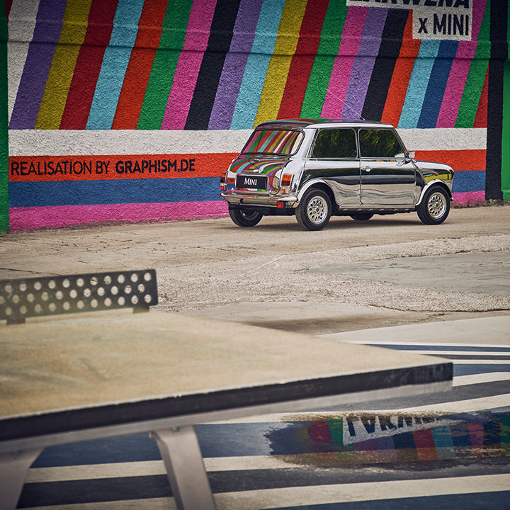 historic, silver MINI standing in front of a colorful striped wall