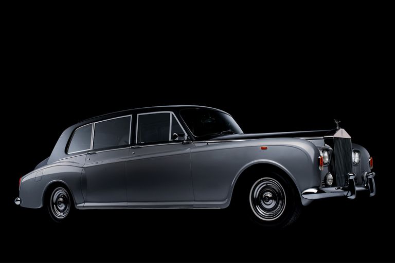 Seitenansicht eines historischen, graublauen Rolls-Royce vor schwarzem Hintergrund