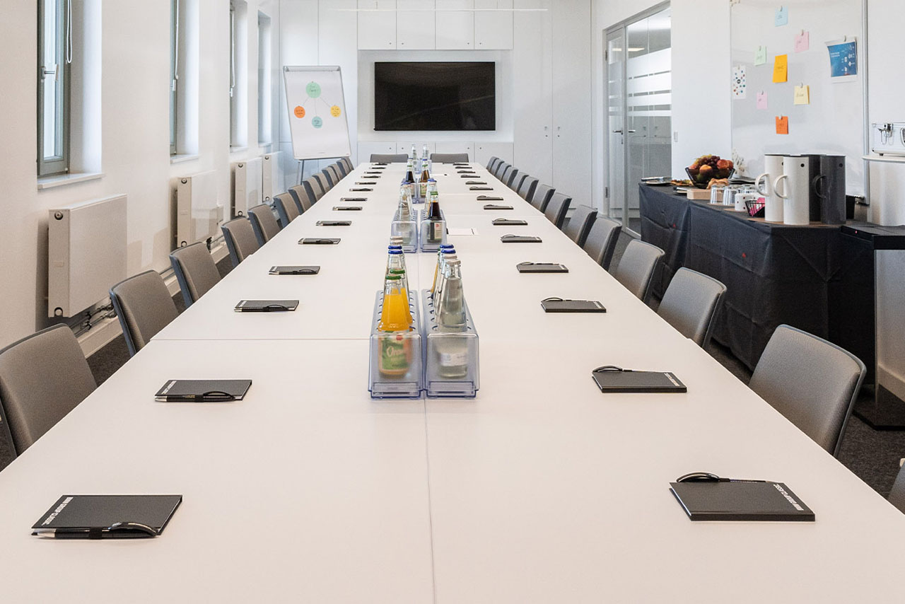 Ein langer Tisch mit einem Fernseher darauf, der eine einladende Atmosphäre für ein BMW Event Forum schafft.