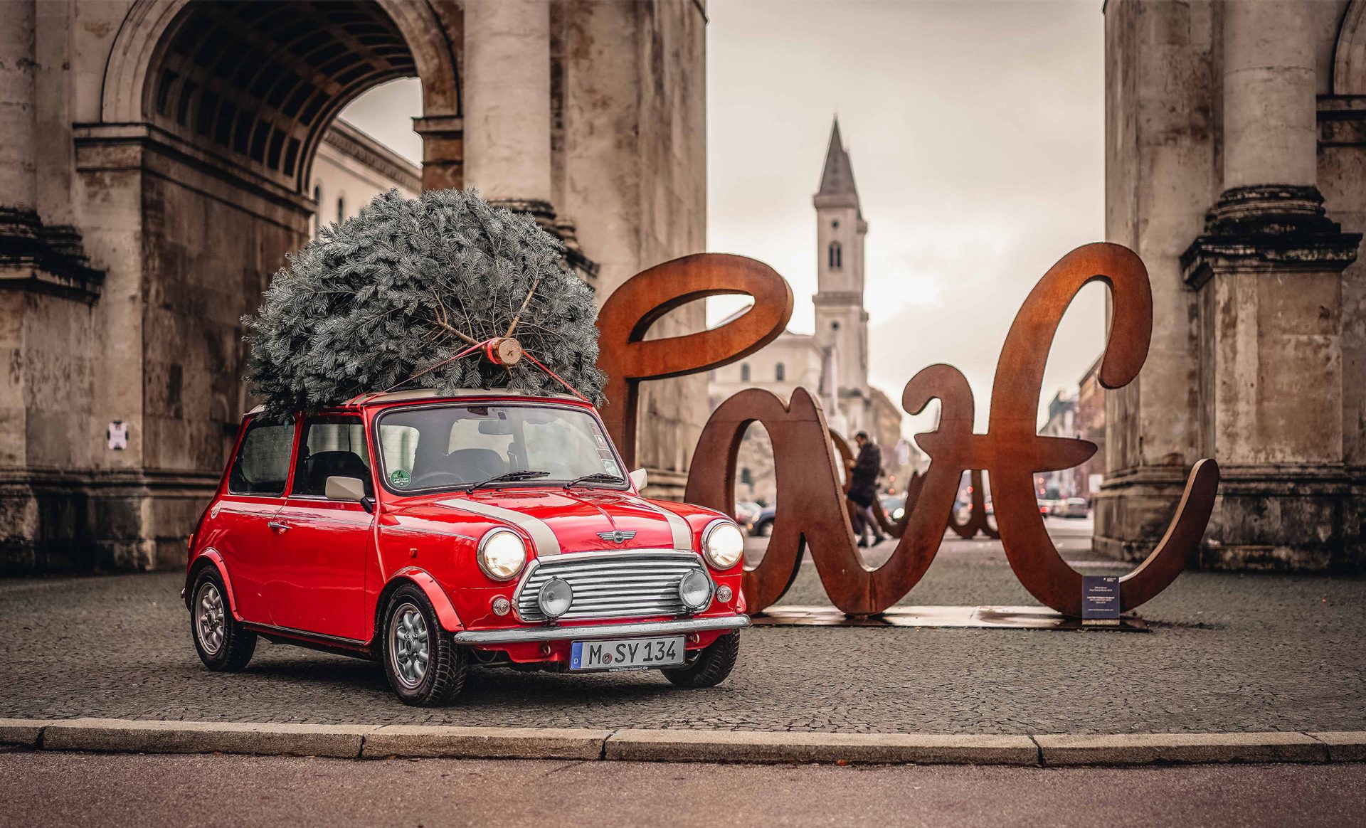 Classic Mini in feuerrot mit Weihnachtsbaum auf dem Dach