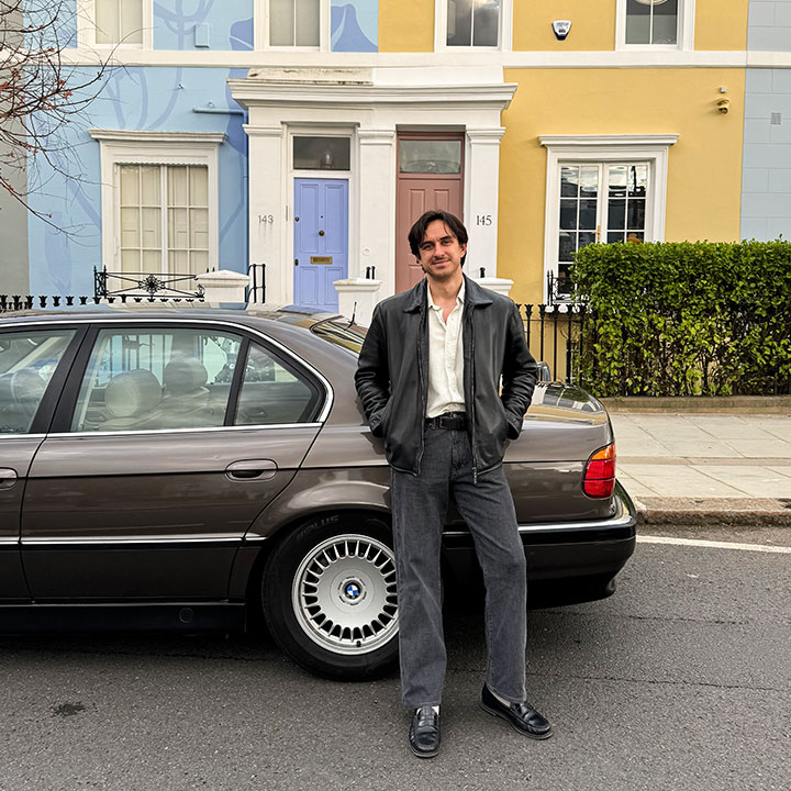 Michal Fidowicz steht neben dem Kofferraum seines BMW E38 vor bunten Wohnhäusern