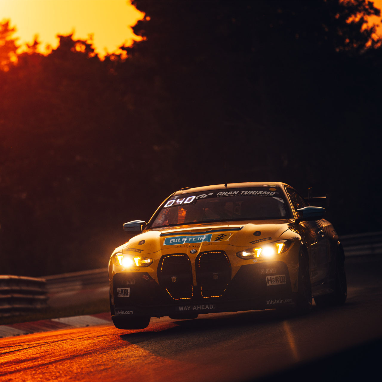 Gelber BMW Rennwagen bei Sonnenuntergang auf einer Rennstrecke