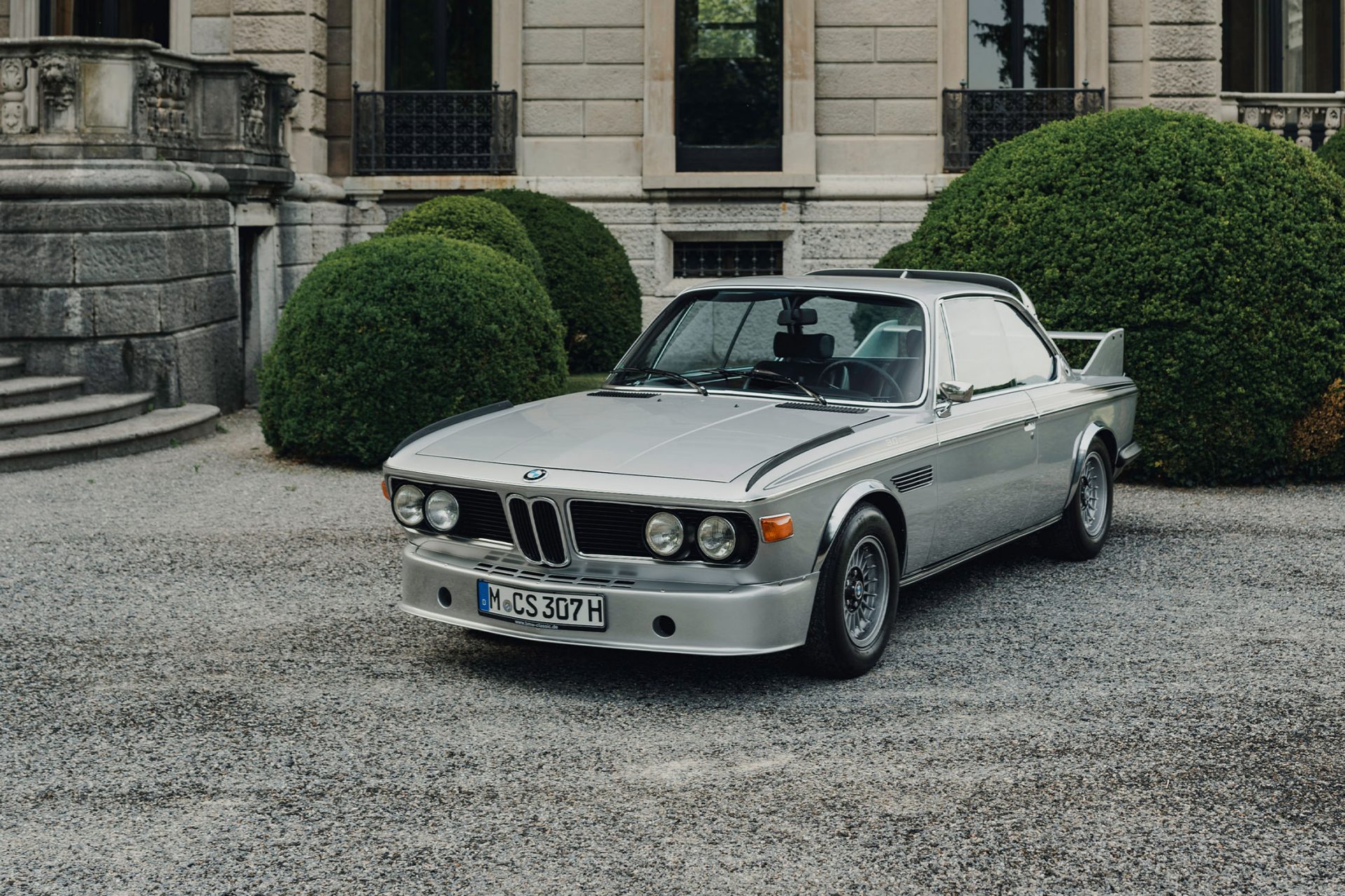 Blick in den Park der Villa d'Este wo ein silberner BMW 3.0 CSL steht.