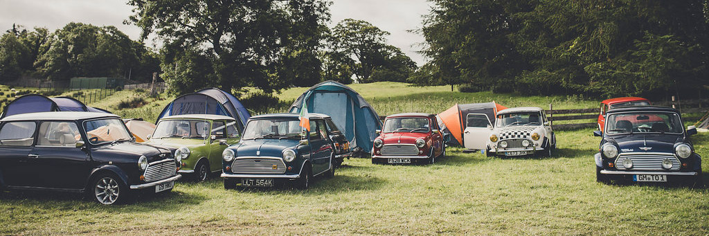 MINI Oldtimer, die auf dem Rasen des Laughton Showground geparkt sind, mit Zelten hinter den Fahrzeugen.