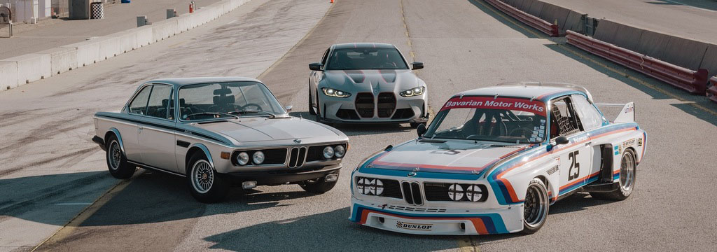 Drei BMW-Fahrzeuge auf einer Rennstrecke, darunter ein klassischer Rennwagen mit der Startnummer 25, ein älteres Coupé und ein moderner SUV.