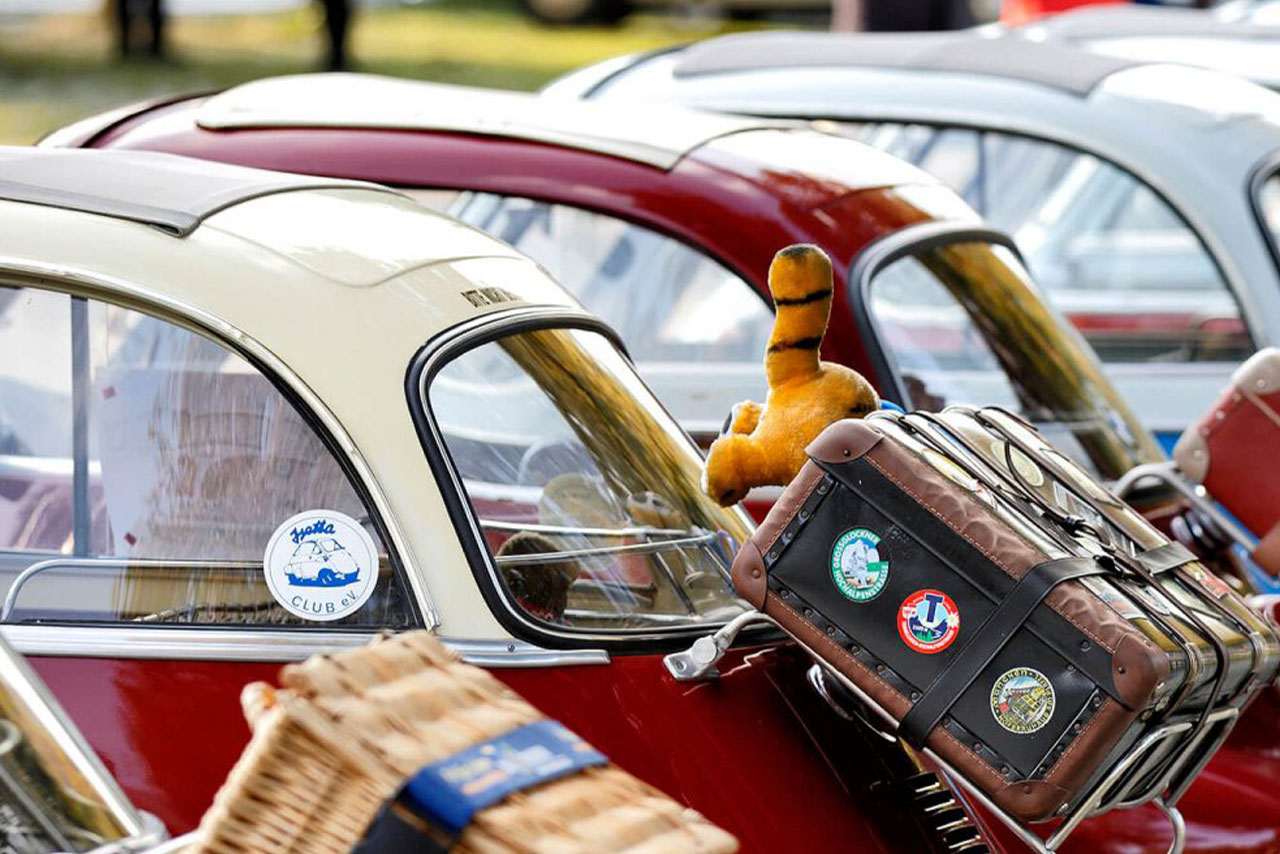 Eine Reihe von BMW Isetta mit einem Stofftier auf dem Rücksitz, das nostalgische Erinnerungen weckt.