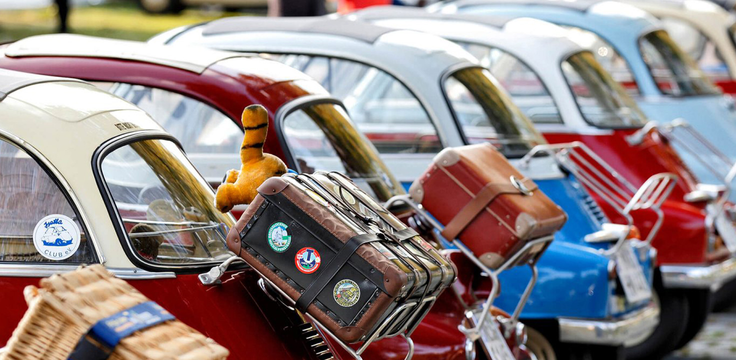 Eine Reihe von BMW Isetta mit einem Stofftier auf dem Rücksitz, das nostalgische Erinnerungen weckt.