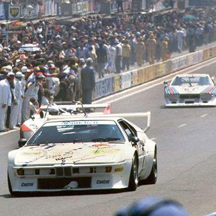 BMW M1 Rennwagen während des Rennens bei den 24 Stunden von Le Mans, umgeben von anderen Fahrzeugen auf der Strecke.