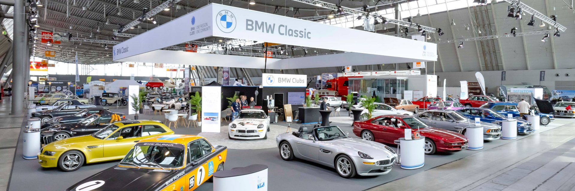 Ein großer BMW Classic Ausstellungsraum mit zahlreichen ausgestellten Autos in verschiedenen Modellen und Farben.