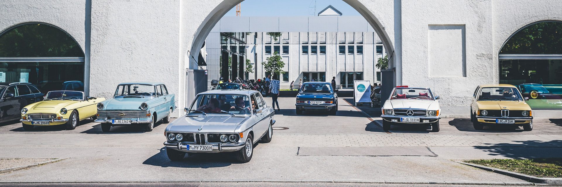 Mehrere Oldtimer vor dem Eingang der Bayrischen Motoren Werke