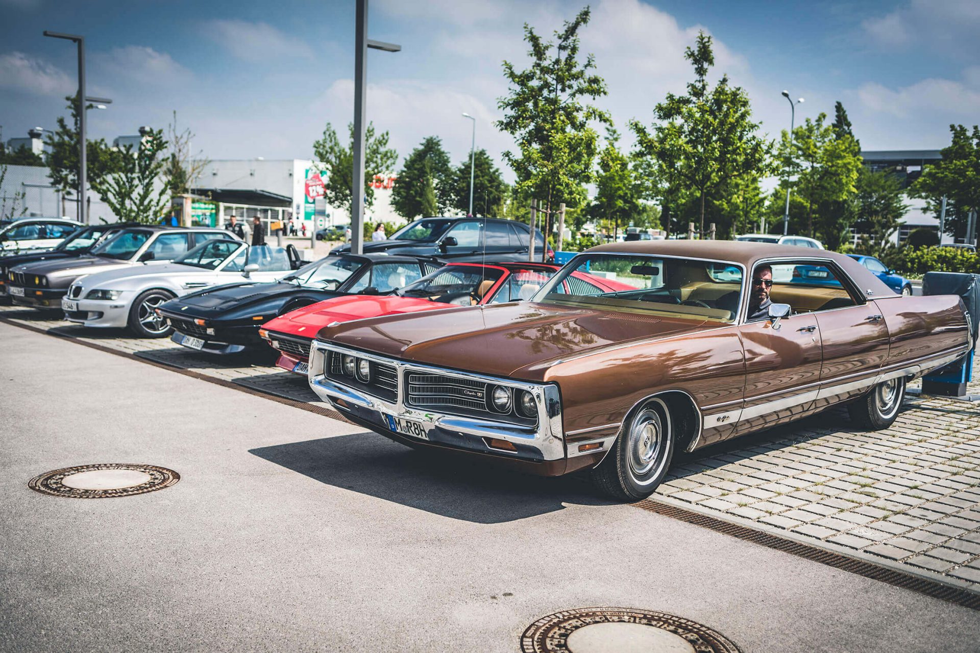 Oldtimer Klassiker aus Amerika, Italien und Deutschland auf einem Parkplatz.