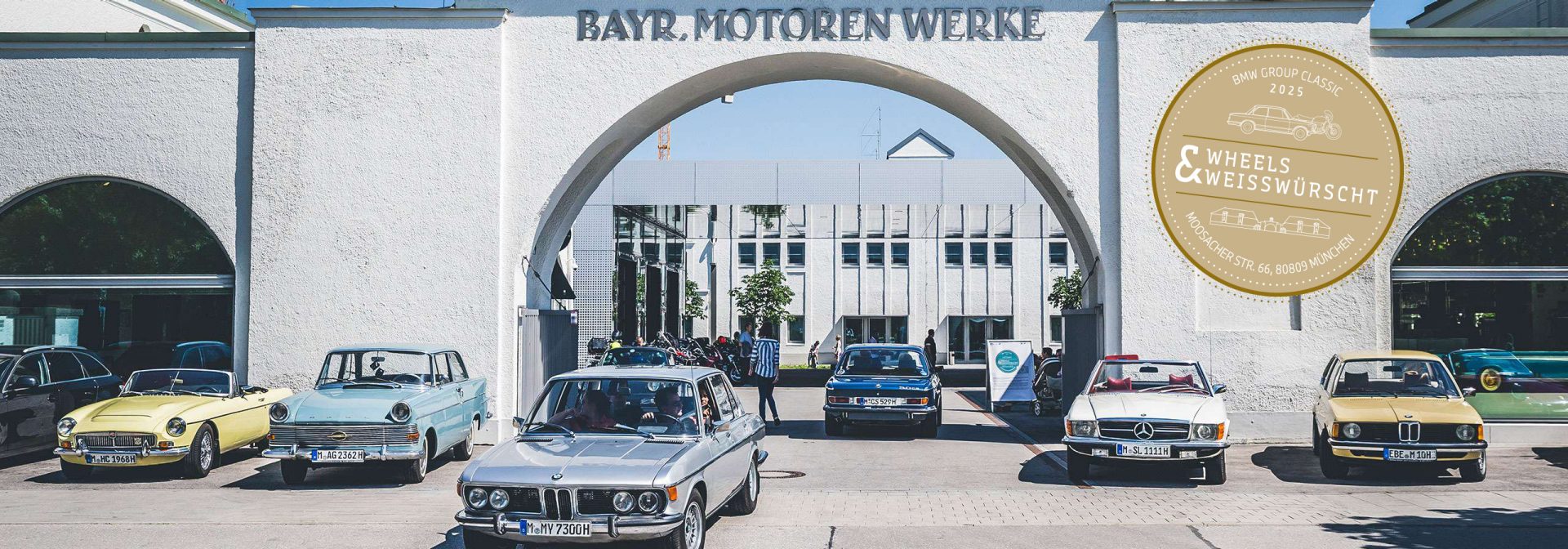 Eingangsbereich der BMW Group Classic mit einigen Automodellen im Vordergrund.