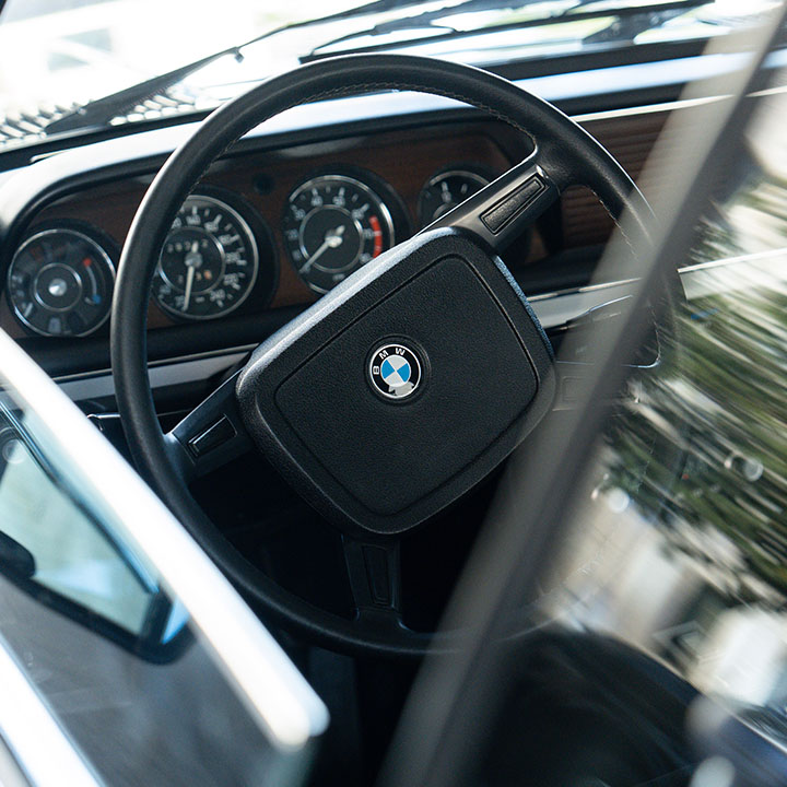 Lenkrad und Dashboard eines BMW Classic Fahrzeugs, die die Instrumente und Bedienelemente für den Fahrer darstellen.