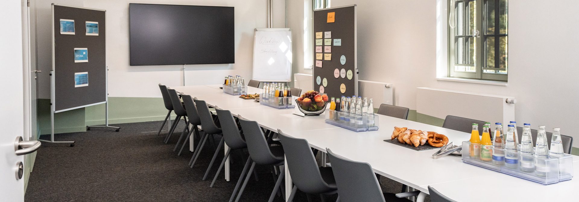 BMW Classic Konferenzraum mit einem weißen Tisch und Stühlen, ausgestattet für professionelle Meetings und Diskussionen.