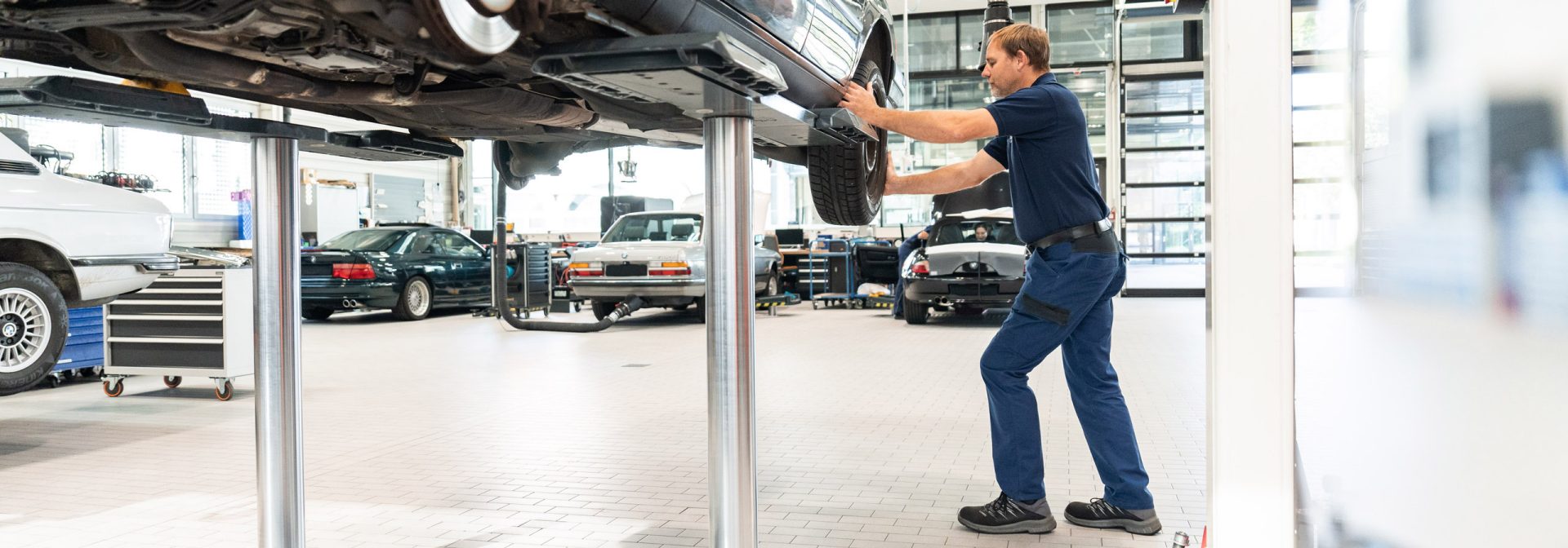 Ein Mann arbeitet an einem Auto in einer BMW Classic Garage, um Reparaturen durchzuführen und die Leistung zu verbessern.