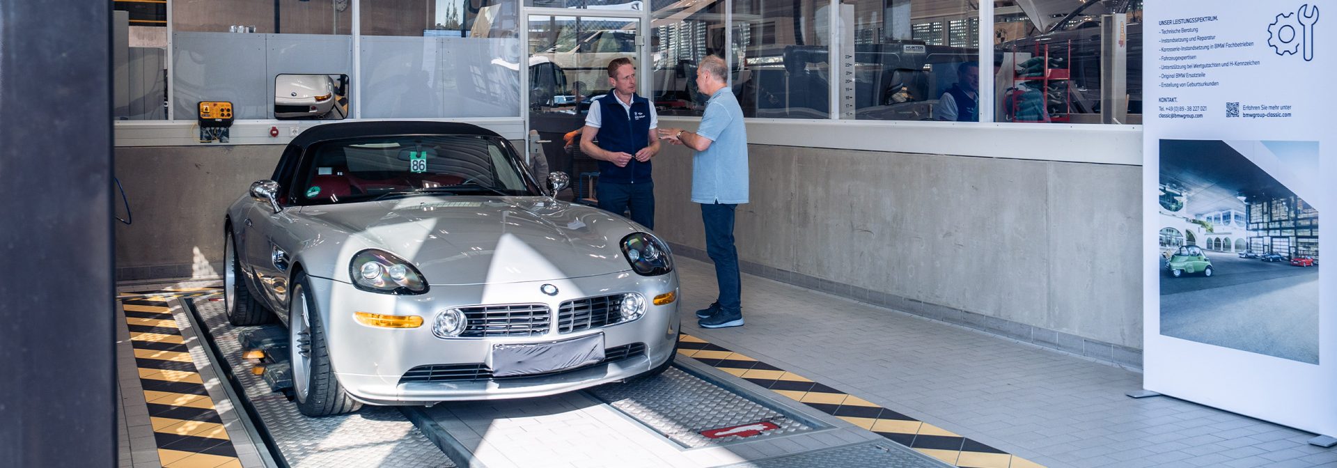 Zwei Männer stehen neben einem BMW-Sportwagen und posieren für ein Foto.