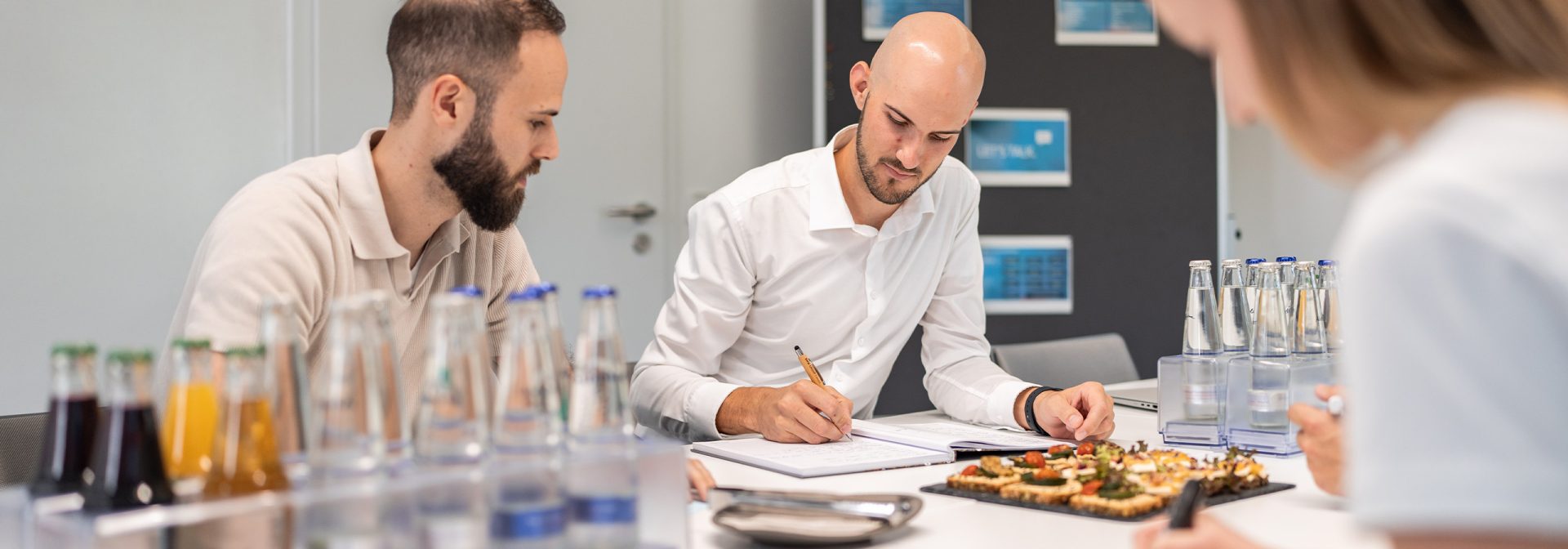 Drei Personen sitzen an einem Tisch, umgeben von verschiedenen Speisen und genießen gemeinsam eine Mahlzeit.