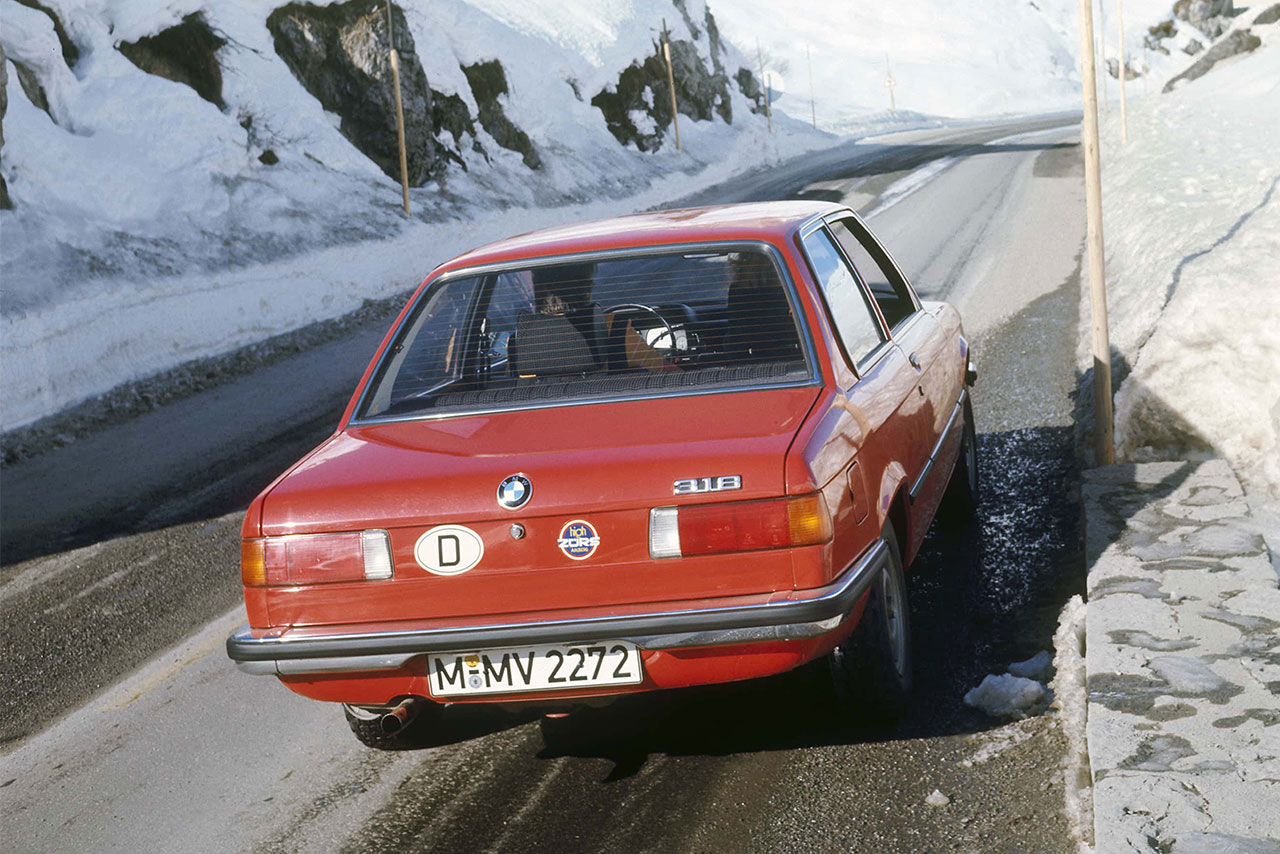 Heckansicht eines 3er BMW der ersten Generation auf einer verschneiten Bergstraße