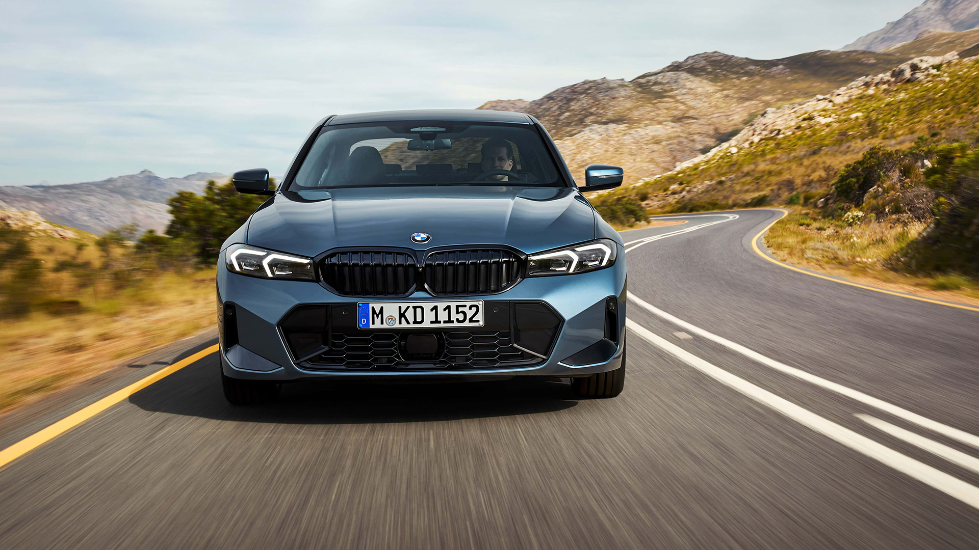 Frontansicht eines blauen 3er BMW der 7. Generation auf einer Landstraße