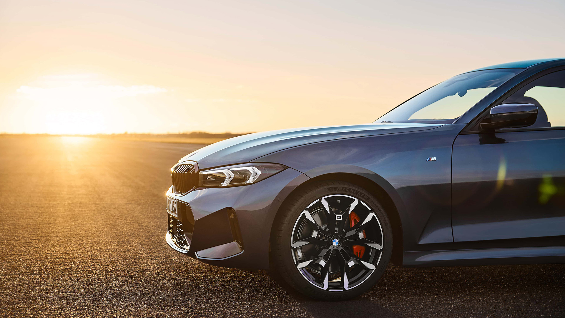Seitliche Frontansicht eines dunkelblauen 3er BMW der 7. Generation bei Sonnenuntergang