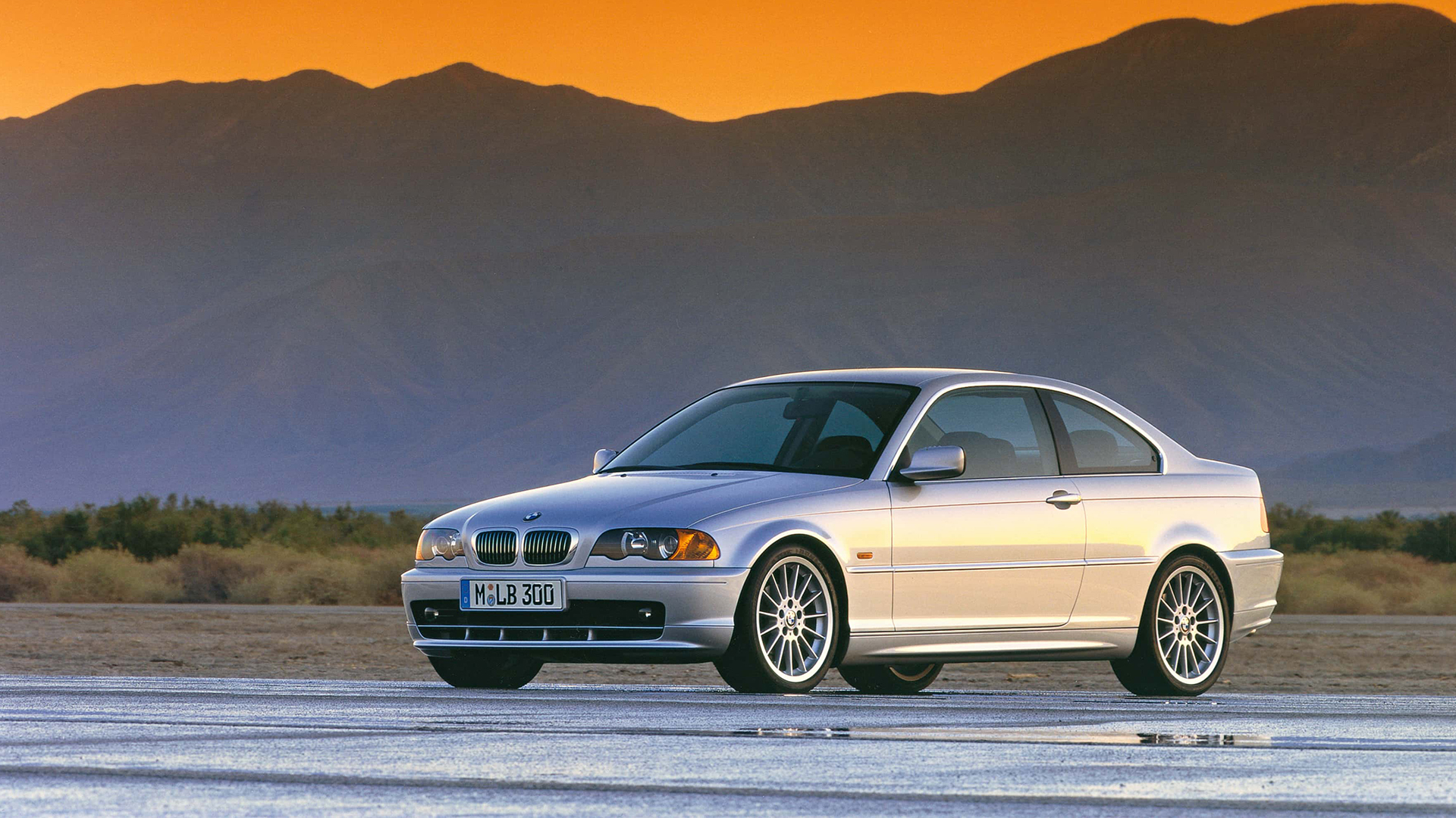 3er BMW der vierten Generation auf einer nassen Straße bei Sonnenuntergang