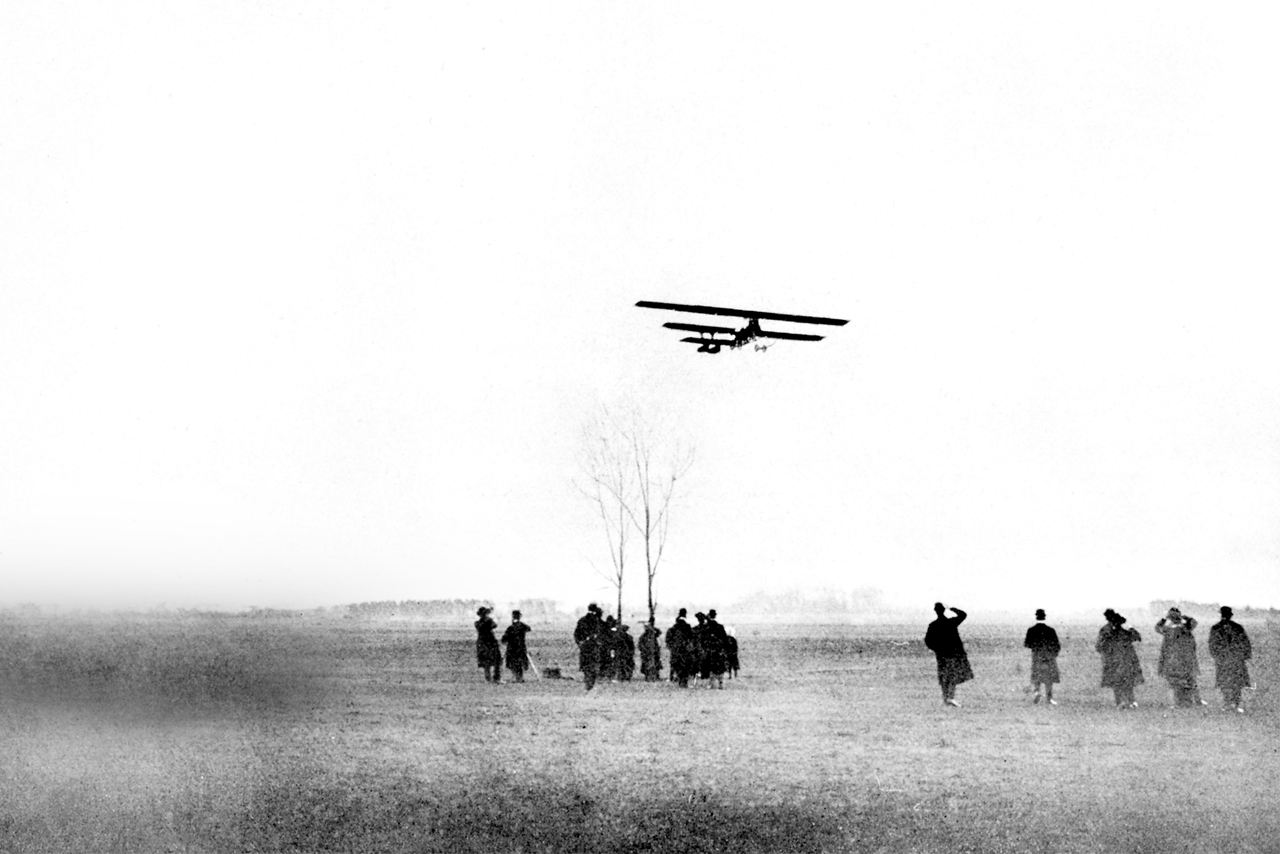 Menschen beobachten BMW Flieger auf dem Feld.