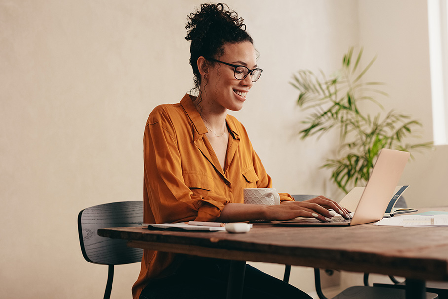 A woman is sitting at a table working on a PC.