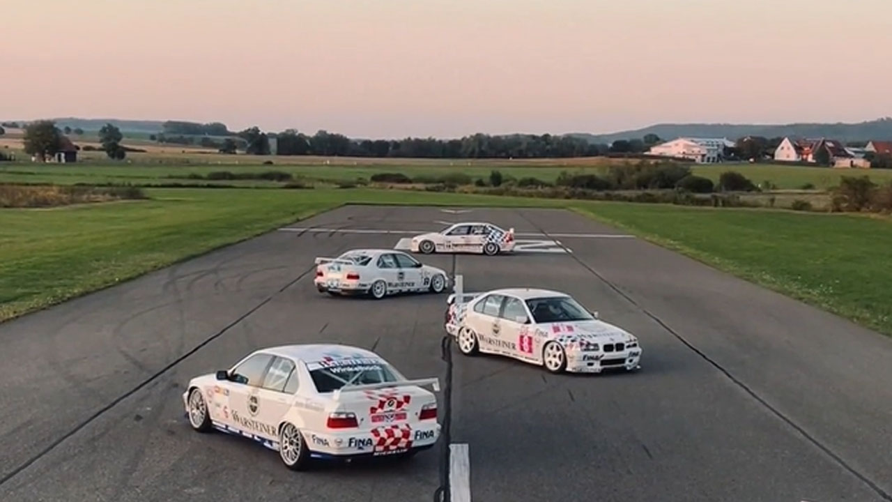 Four vehicles move along a road lined with grass.