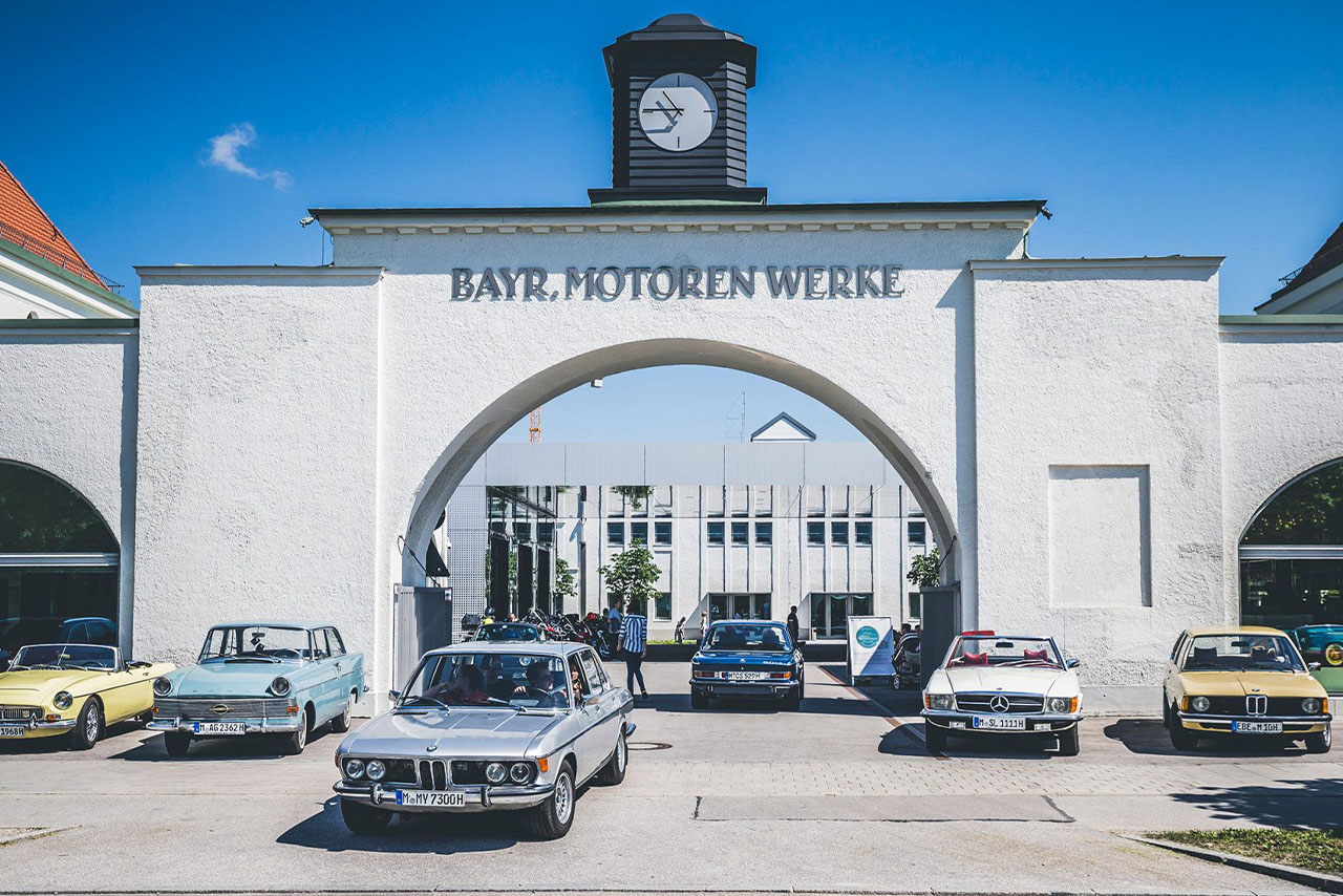 Numerous classic cars of different brands in front of the portal of the oldest BMW plant in Munich, which now houses the BMW Museum.