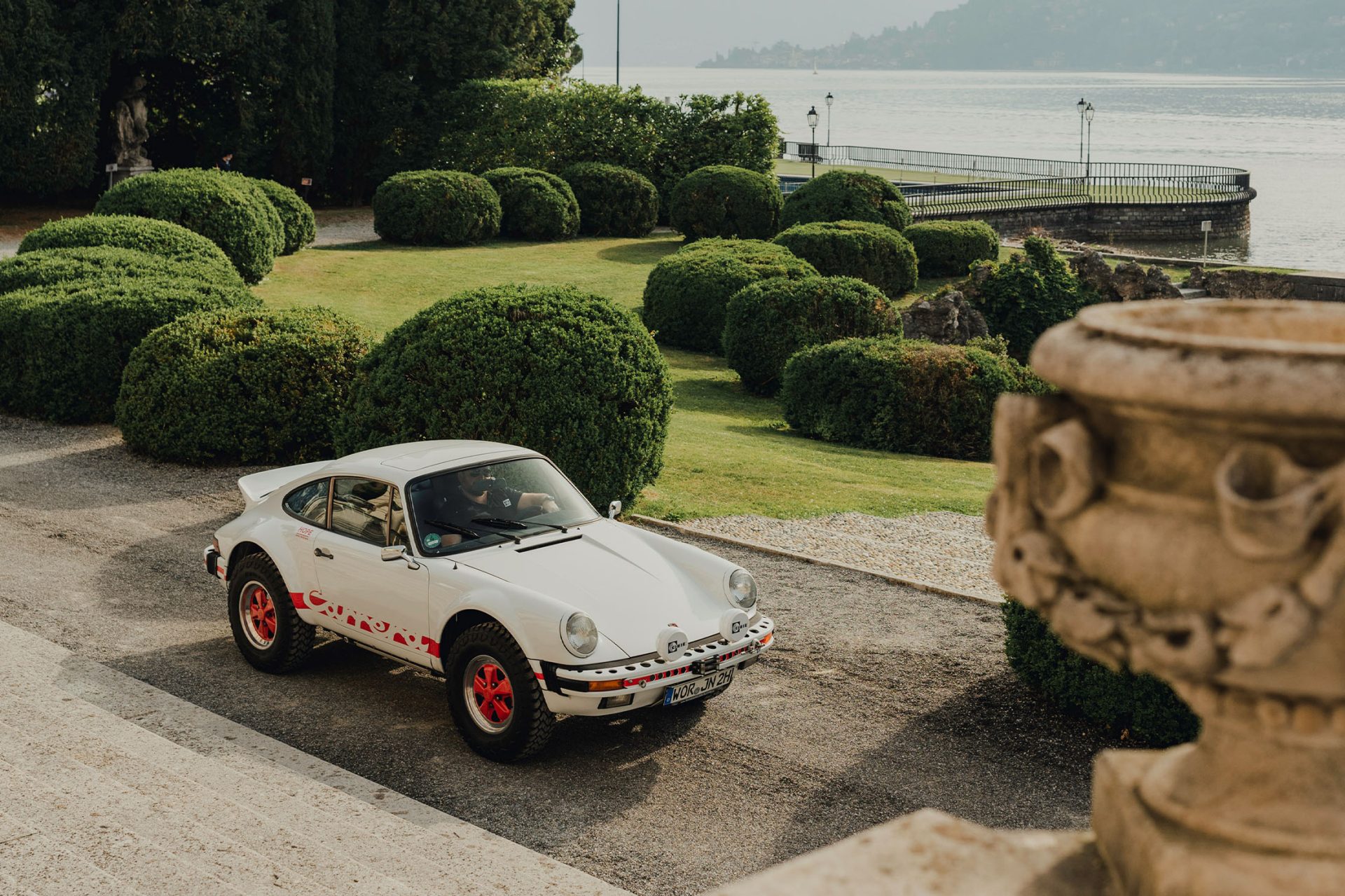 View of the park of the Villa d'Este where a white 911 classic is parked.