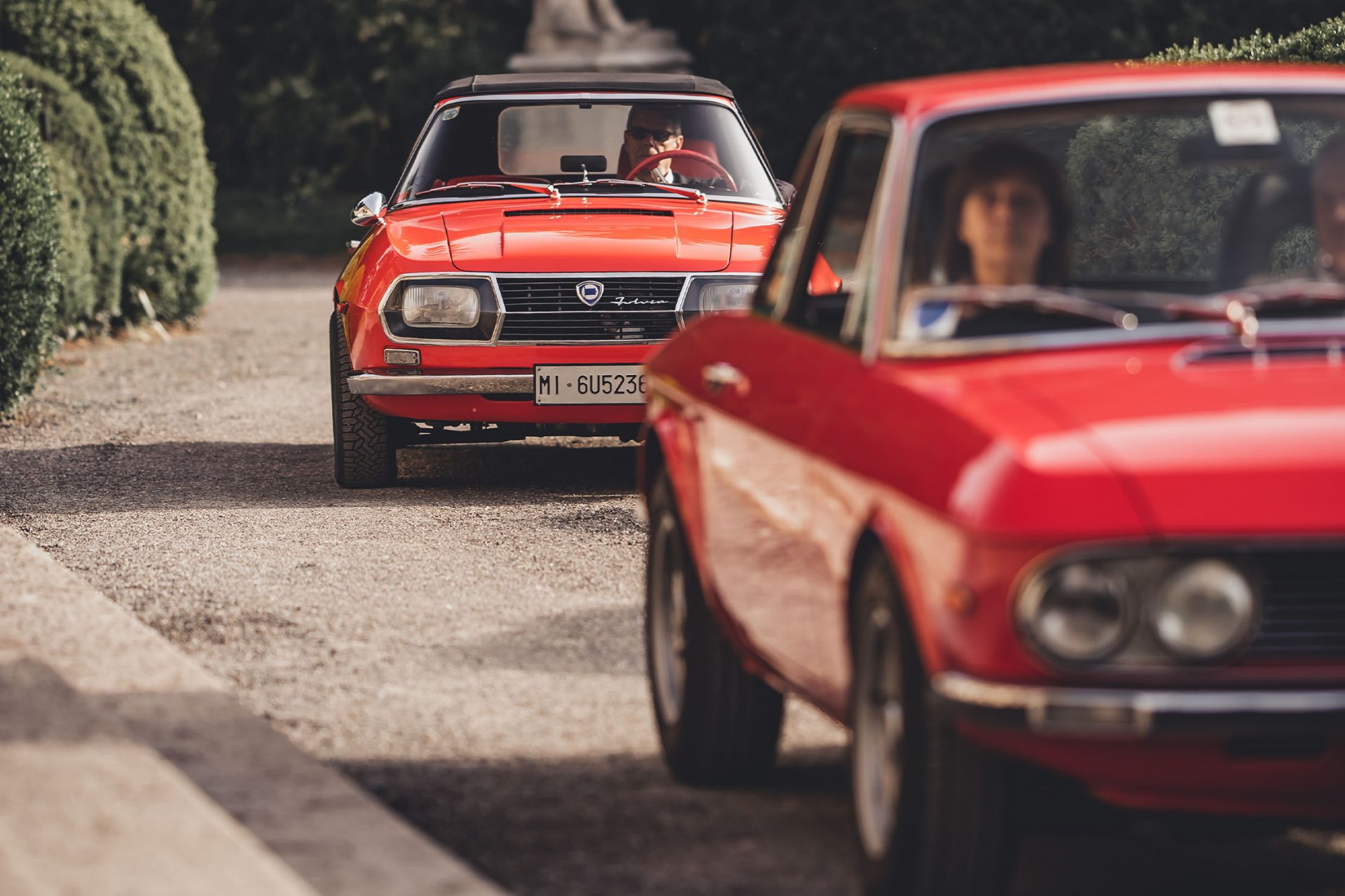 View of the Villa d'Este park, through which two red classic cars are currently driving.