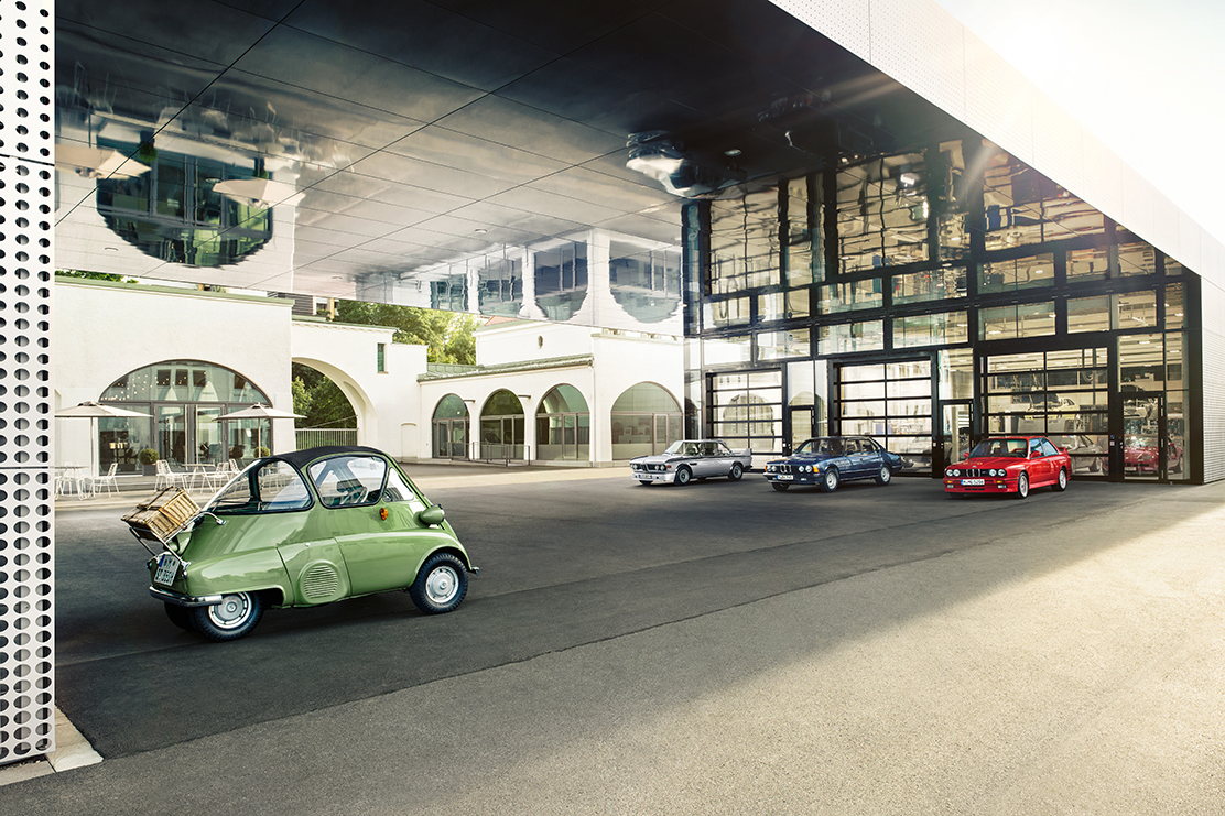 Outdoor area with a metallic green Isetta and three other classic BMWs.