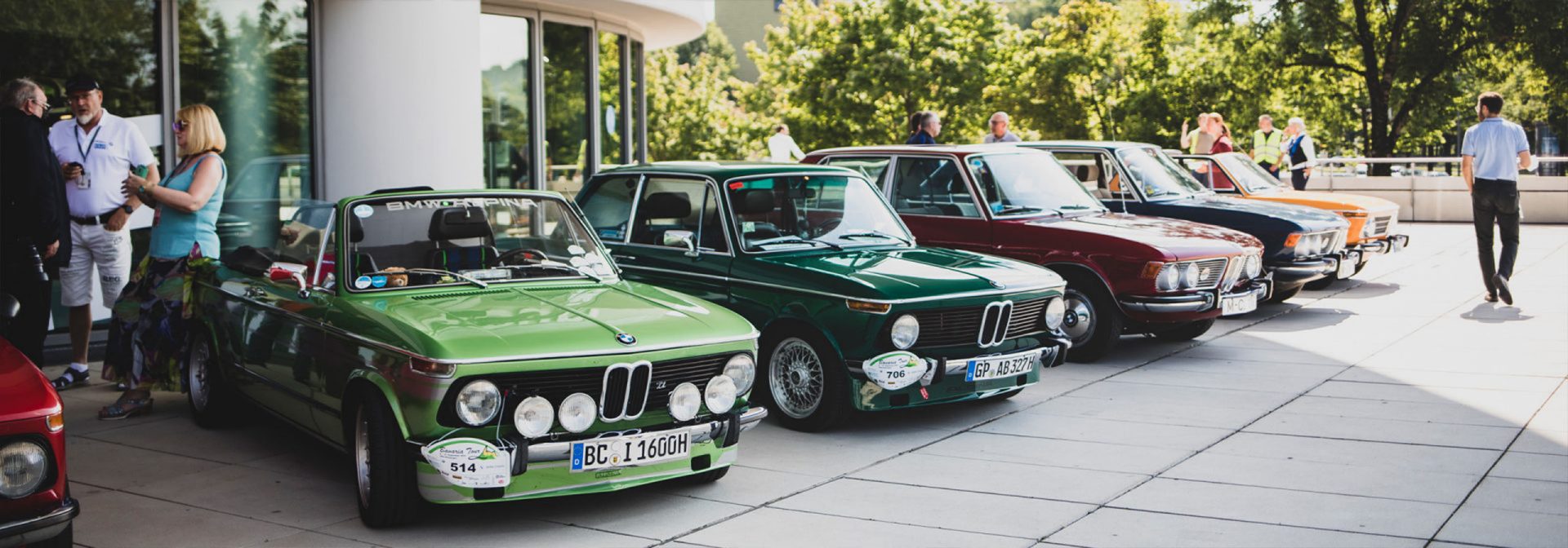 BMW Classic cars are lined up in front of a historic building, lending the scene a charming character.