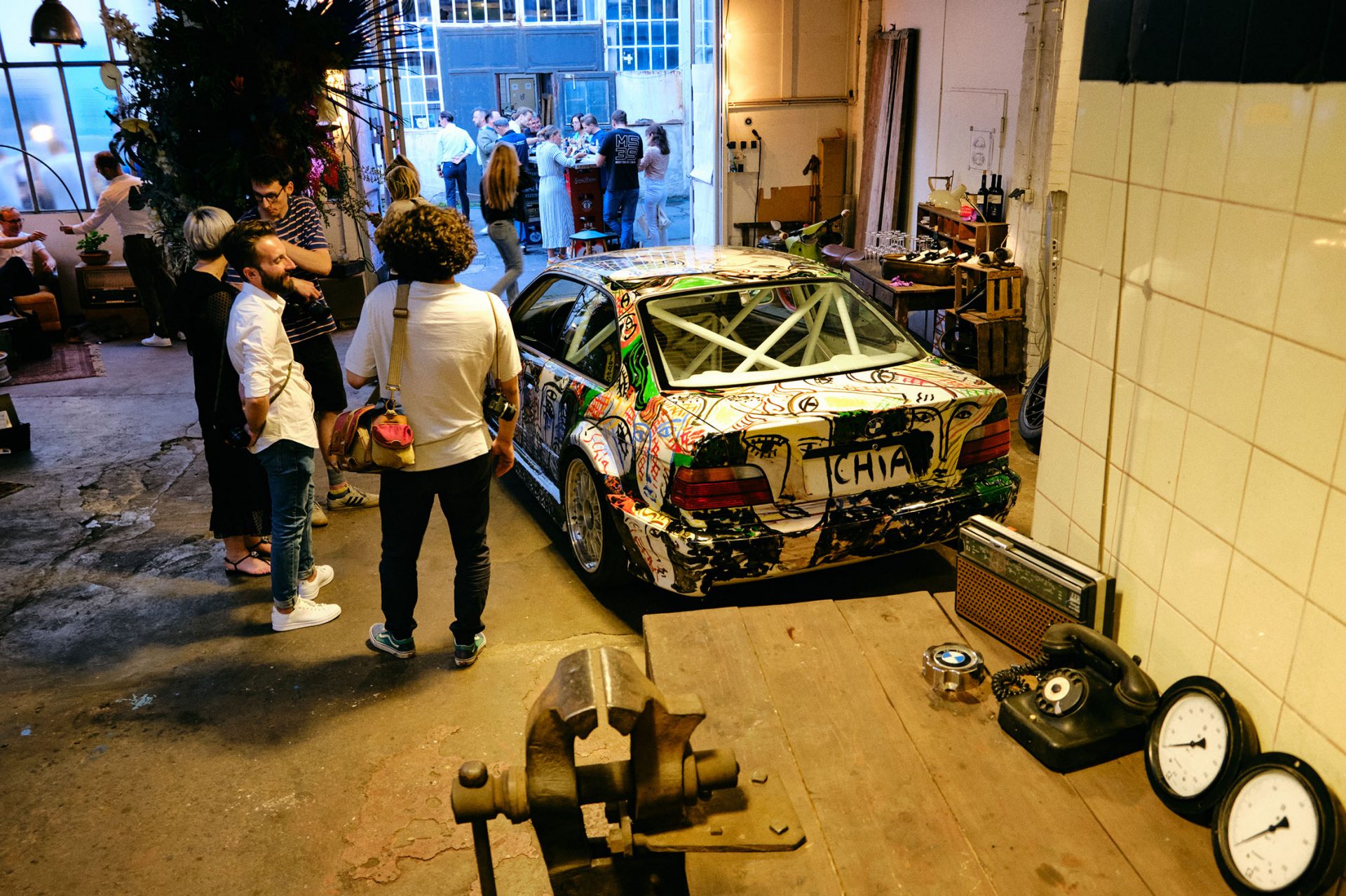 View of a group of visitors admiring a BMW Motorsport vehicle with a roll cage.