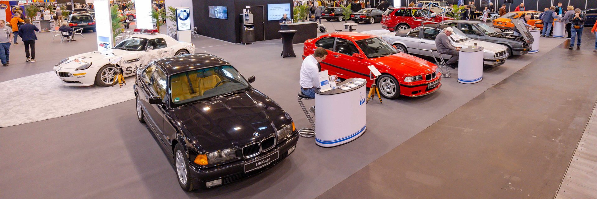 In a spacious BMW Classic showroom, numerous cars are on display, attracting the attention of visitors.