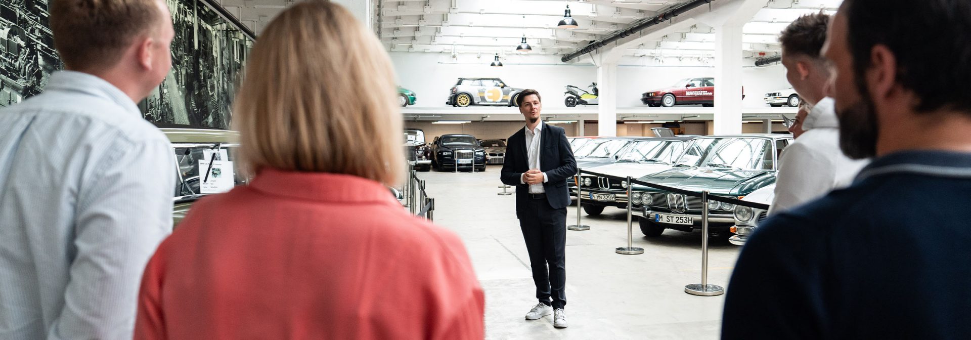 Three visitors are on a guided tour of the BMW Group Classic exhibition.