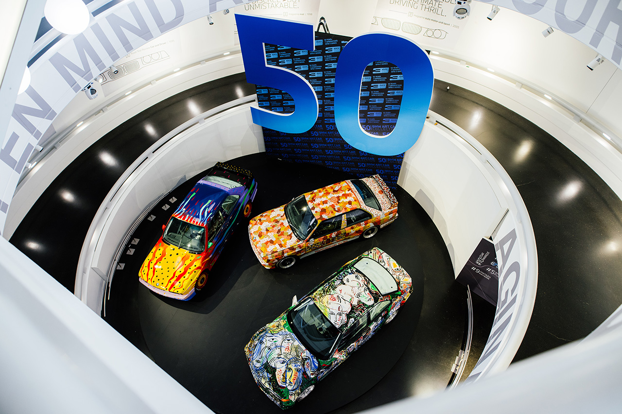 In the BMW Museum, BMW Art Cars and BMW 3 Series models are arranged in a circle, with a large 50 emblazoned above the vehicles.