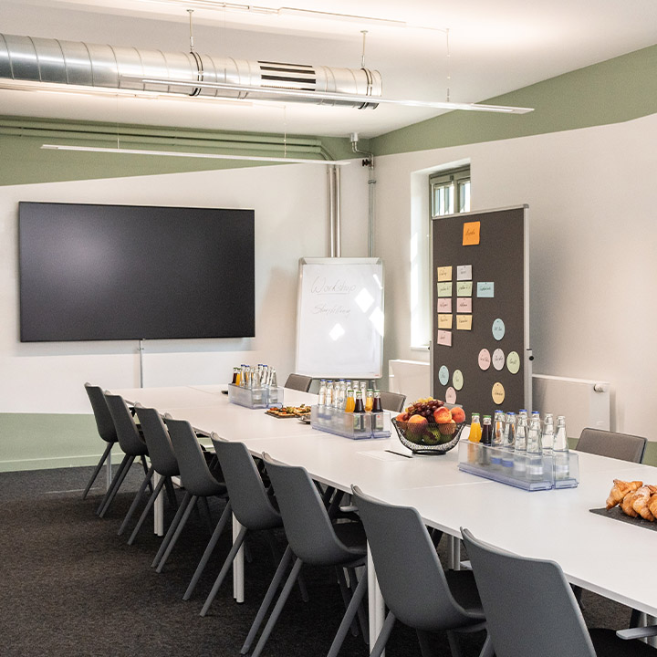 BMW Classic Conference Room equipped with a long table, numerous chairs, a big screen and a whiteboard.