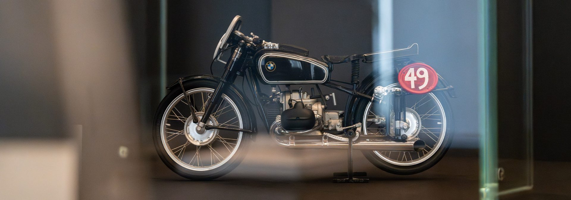A BMW motorcycle is on display in a glass cabinet, attracting the attention of onlookers.