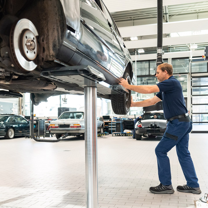 A man works on a car in a BMW Classic Garage to carry out repairs and improve performance.