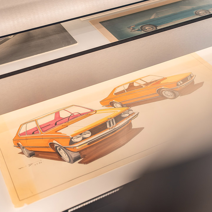 Wall drawing of a BMW car, supplemented by a picture of another vehicle.