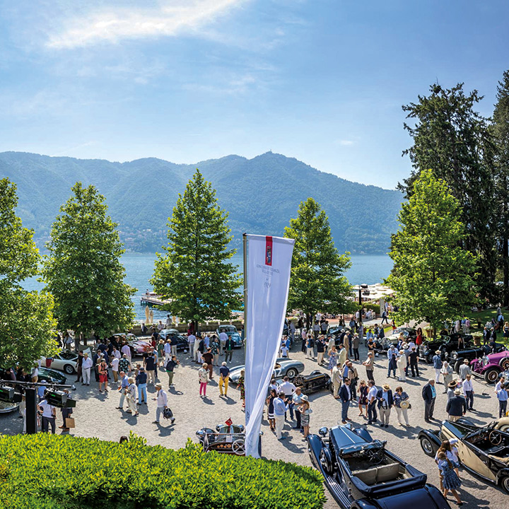 Vintage cars and their owners in the parking lot in front of the Hotel Villa d’Este with the lake and mountains in the background.