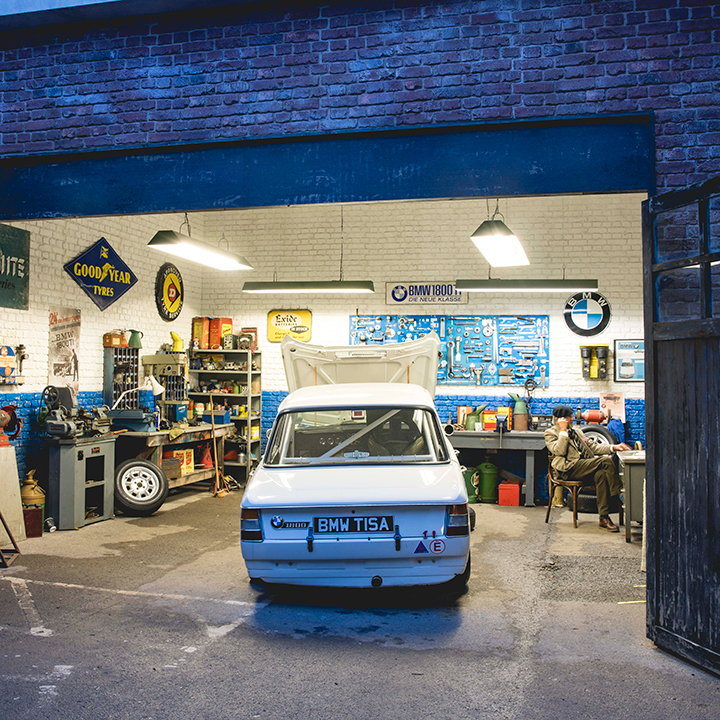 A vintage BMW in a garage with the hood open.