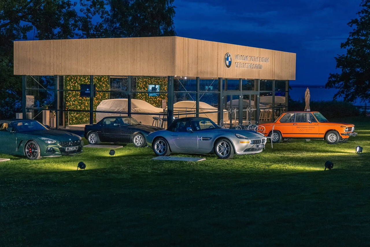 BMW Art Cars parked on a meadow in front of a museum.