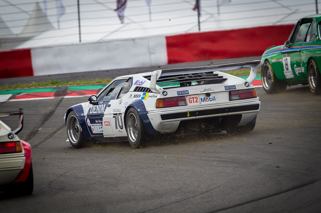 Rückansicht eines historischen, weißen BMW M1 Procar Rennwagens auf der Strecke