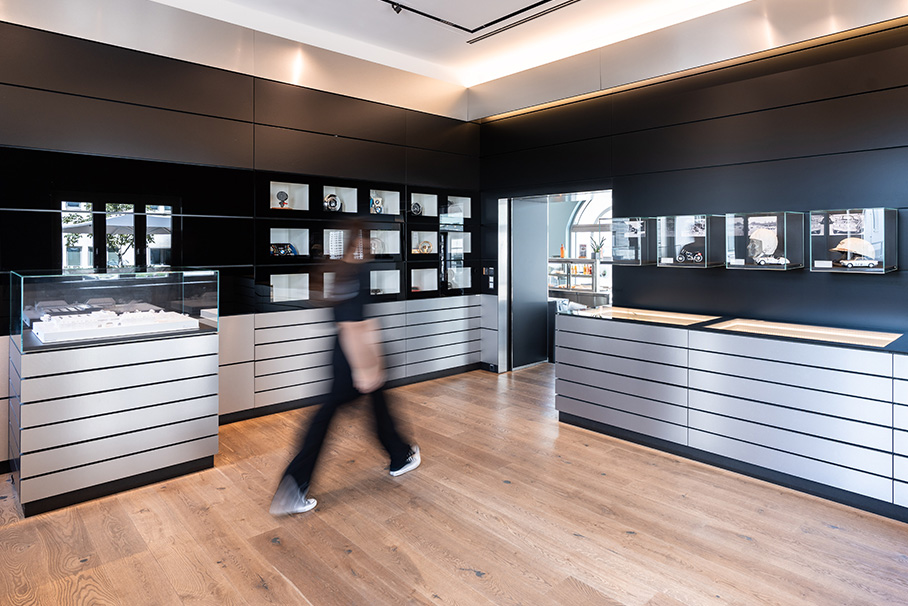 A person walks through the BMW Archive room, surrounded by a variety of jewelry in various displays.