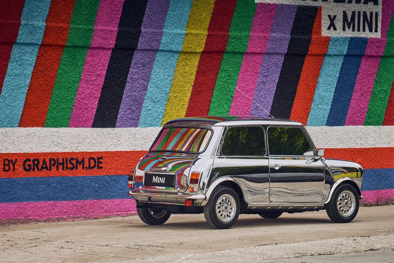 A MINI car stands in front of a colorful wall designed with vibrant colors.
