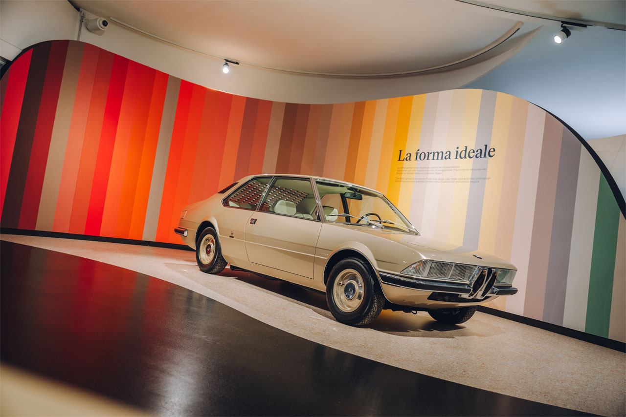A car is exhibited in a museum, surrounded by informative display boards and other exhibits.