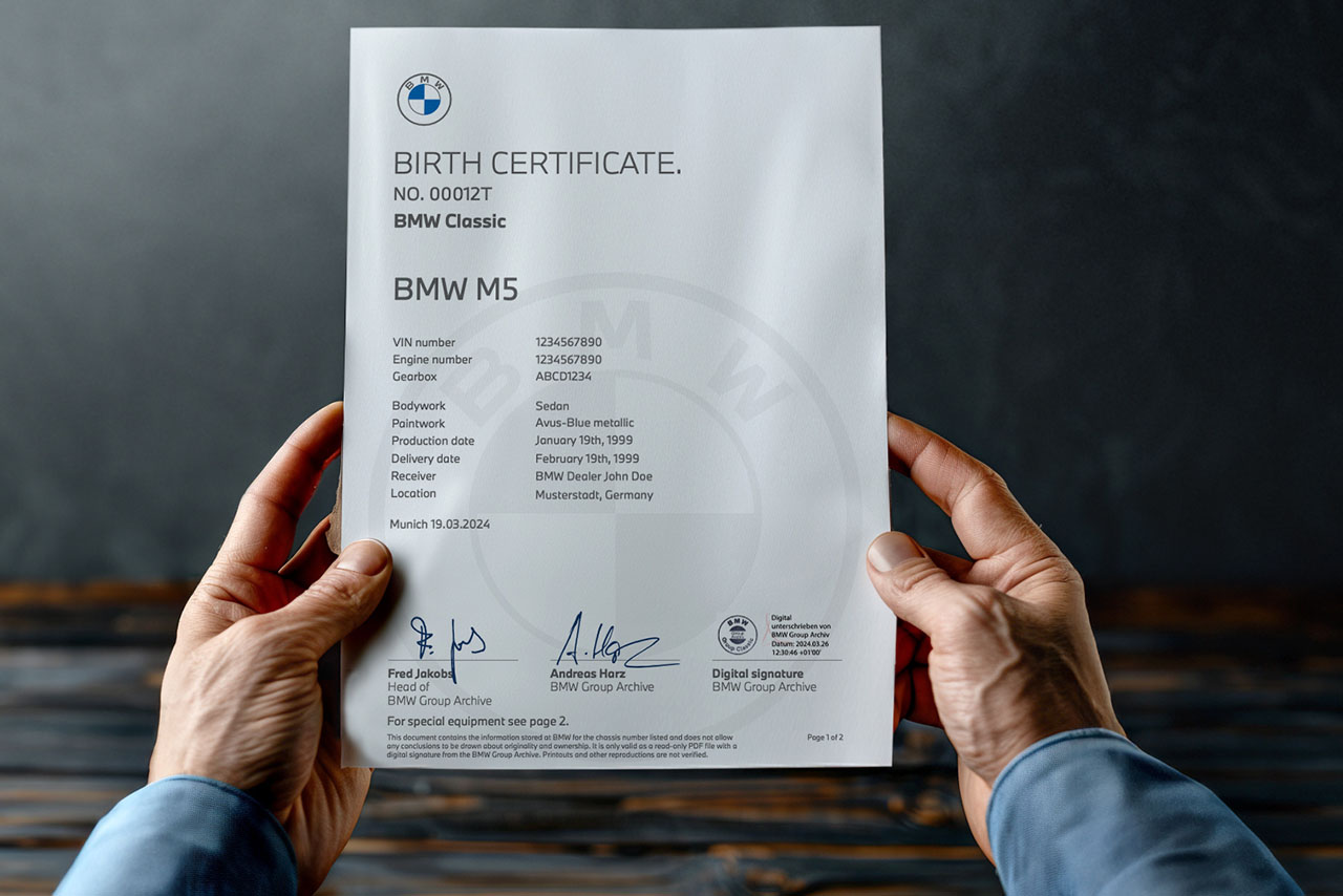 Two hands holding the BMW Birth certificate of a BMW M5
