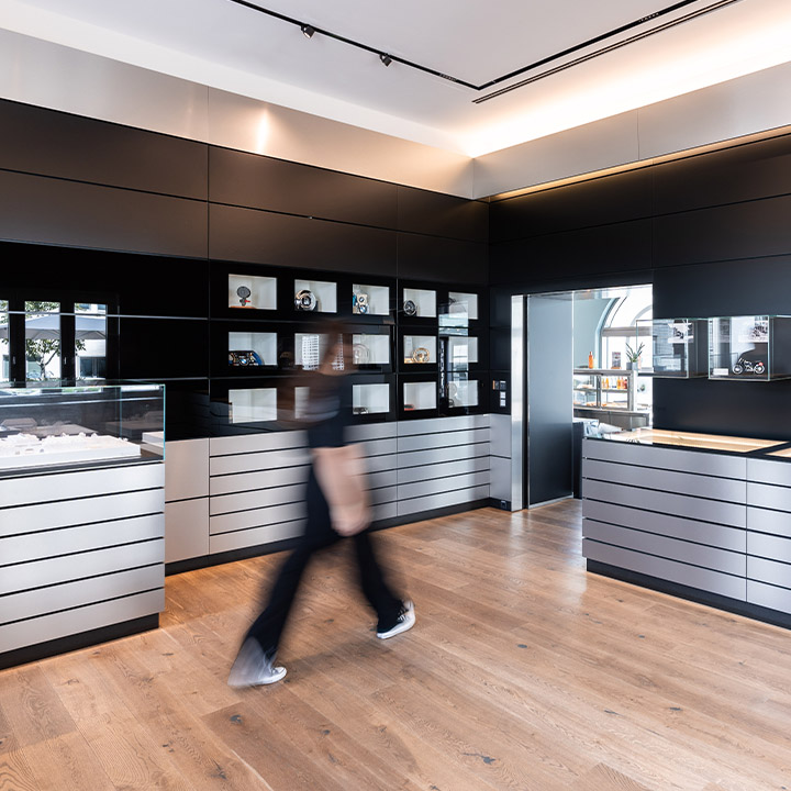 A person walks through the BMW Classic Archive with numerous glass cabinets displaying various products.